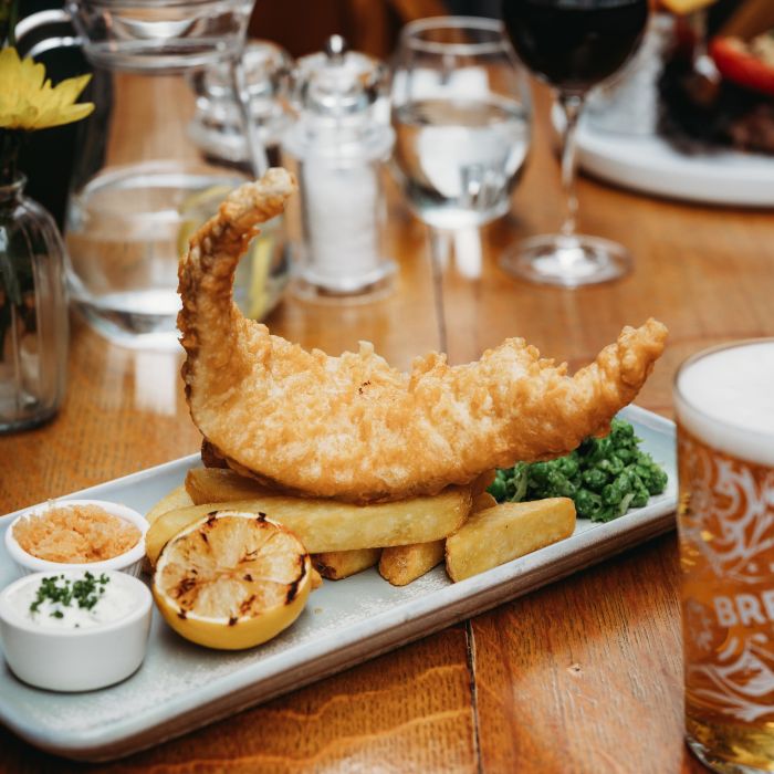 Food and Drink Menus: fish and chips, beer and condiments on a pub table